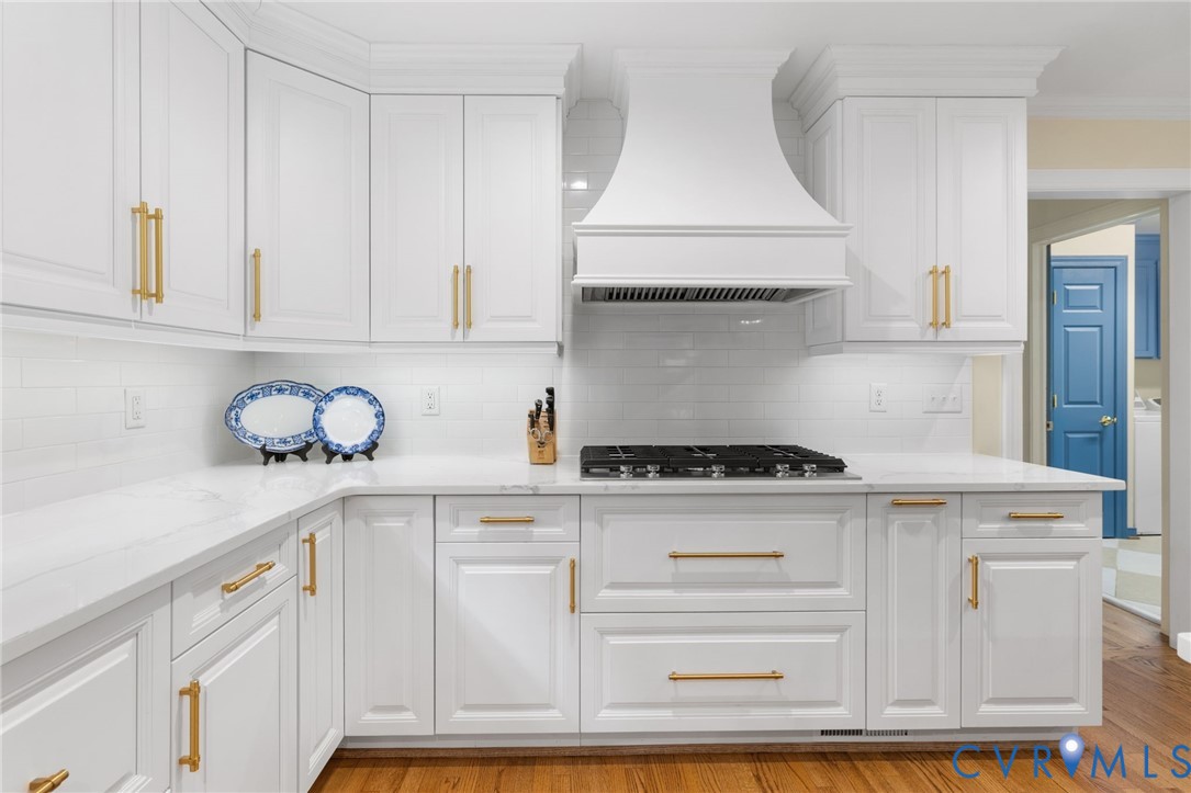White shaker-style cabinetry with gold-tone hardware, white subway tile backsplash, white countertops, and a built-in gas range