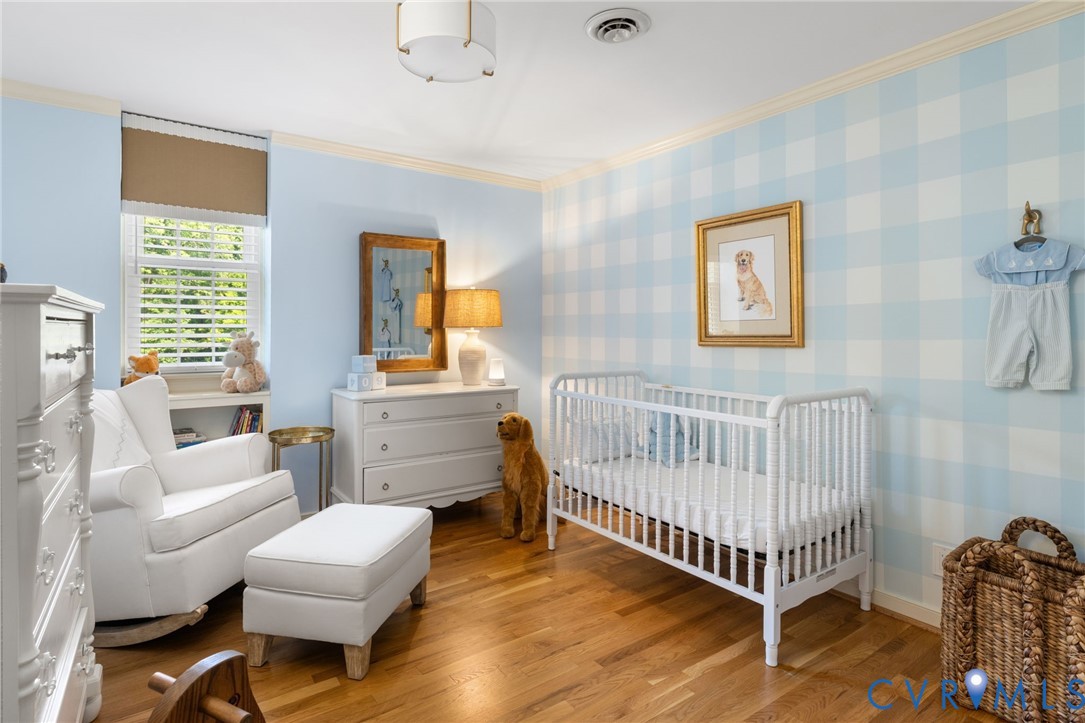 Hardwood flooring, crown molding, double-hung window with privacy blinds, built-in shelving, and a semi-flush mount ceiling fixture