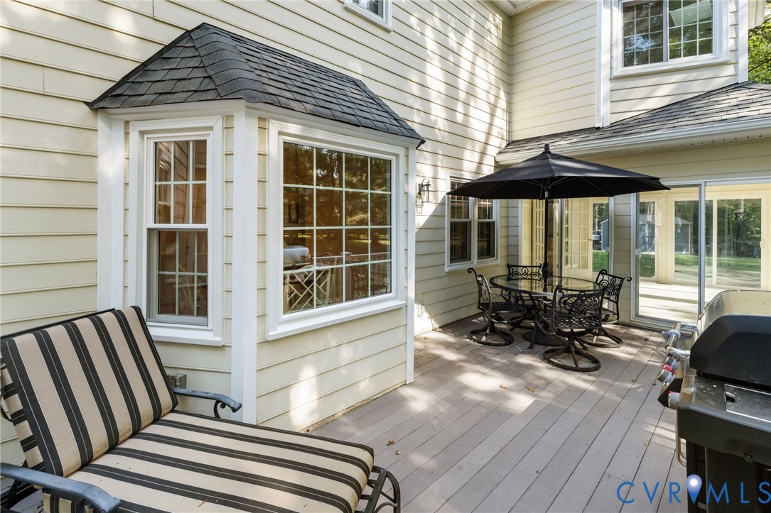 Exterior deck area featuring a bay window with gridded panes, cream-colored siding, and sliding glass doors