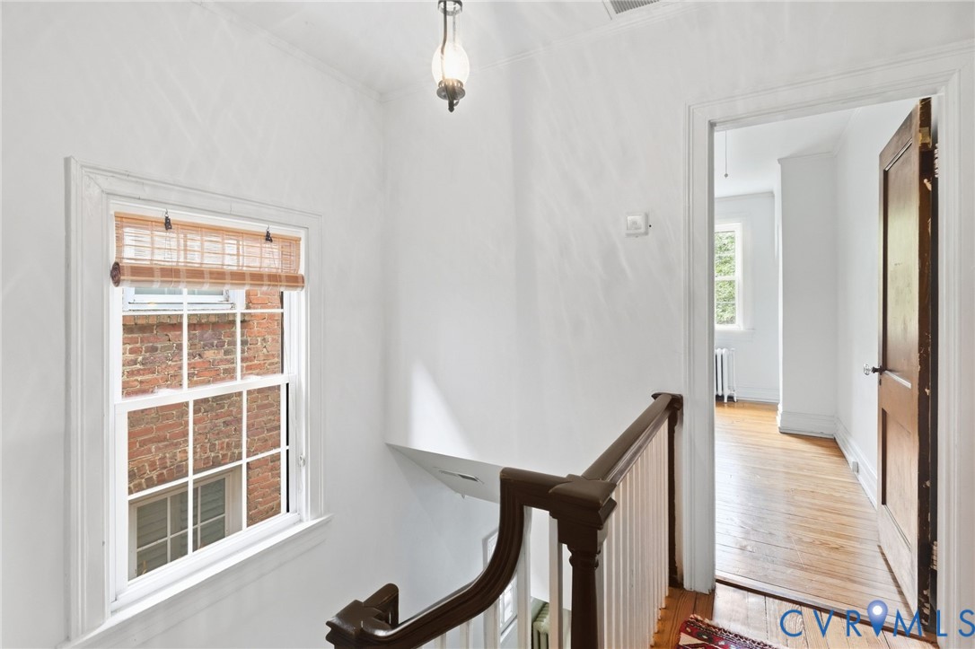 Hardwood flooring throughout, white painted walls, white trim, and a classic wood baluster with a dark wood handrail
