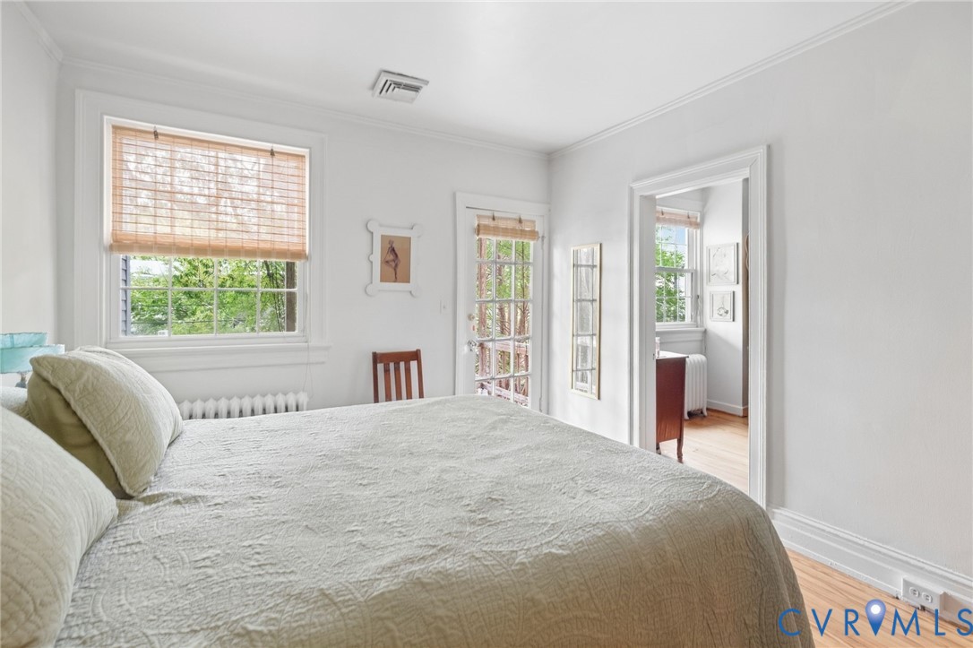 Hardwood flooring, crown molding, white trim work, and a glass-paneled door
