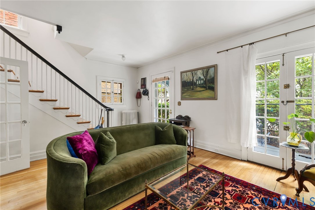 Hardwood flooring, white walls, and a staircase with white risers and a black handrail