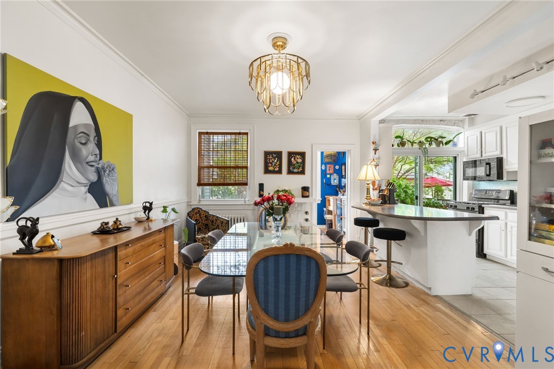 Hardwood flooring, kitchen island with seating, white cabinetry, integrated microwave, and built-in refrigerator