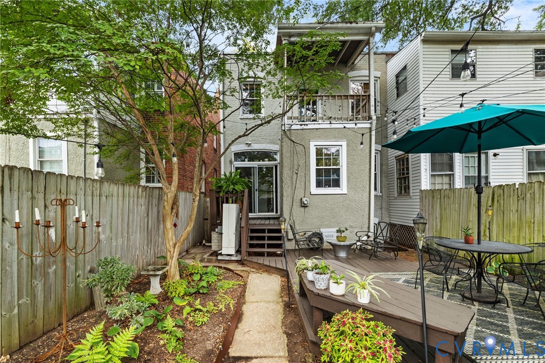 Backyard featuring a privacy fence, multi-level decking, sliding glass door access, and a second-story balcony