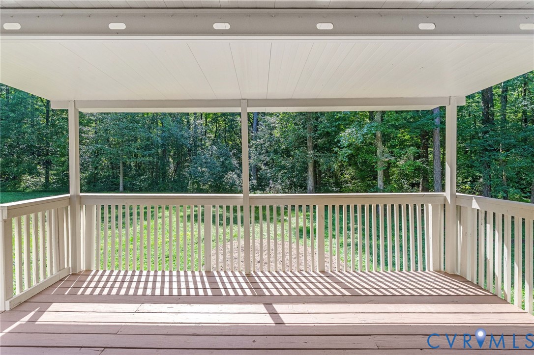 Covered deck featuring wood-finish flooring, white railings, and integrated overhead lighting
