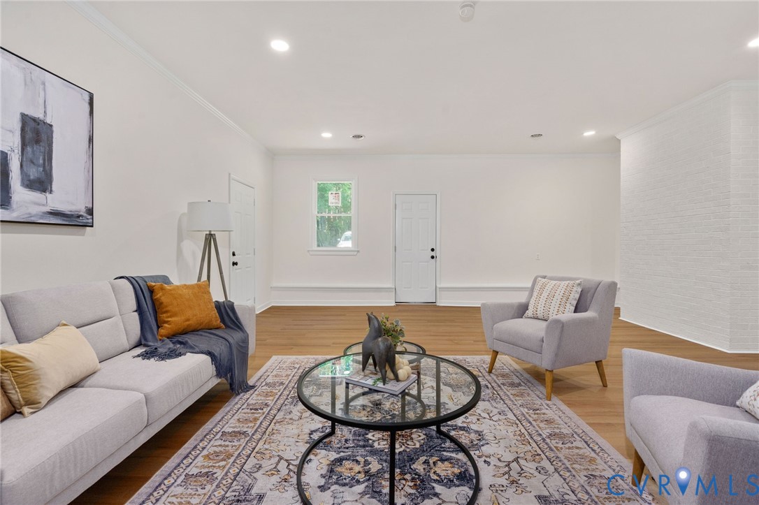 Recessed lighting illuminates the wood-finish flooring and white walls, complemented by crisp crown molding