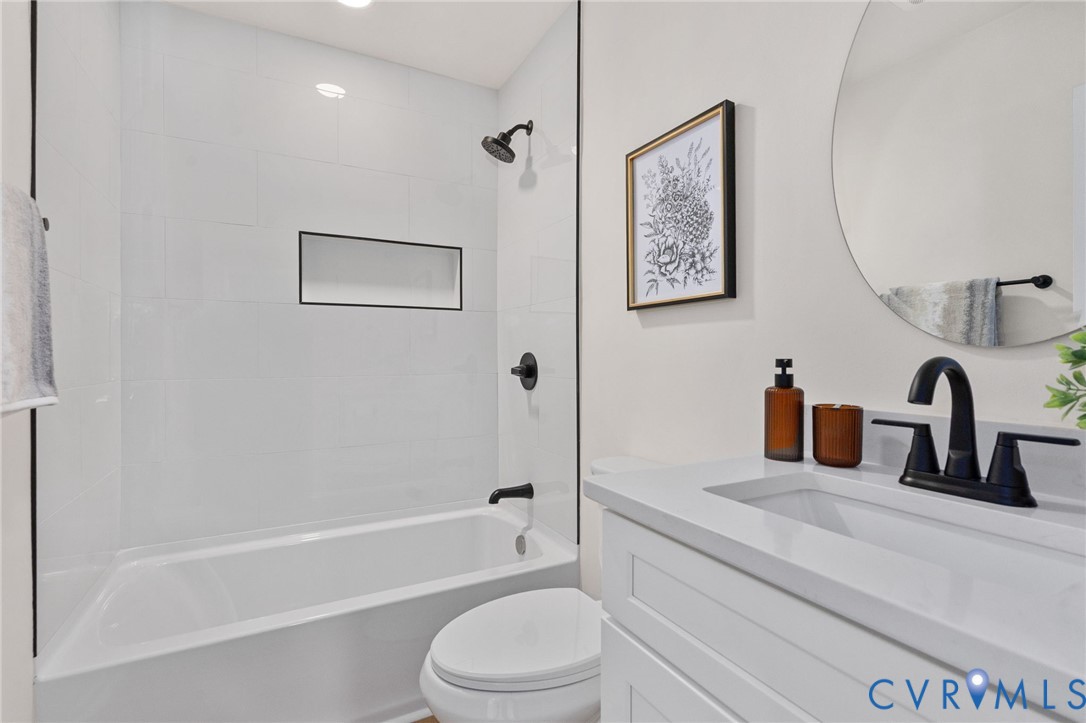 White subway tile tub surround with an integrated black-framed niche