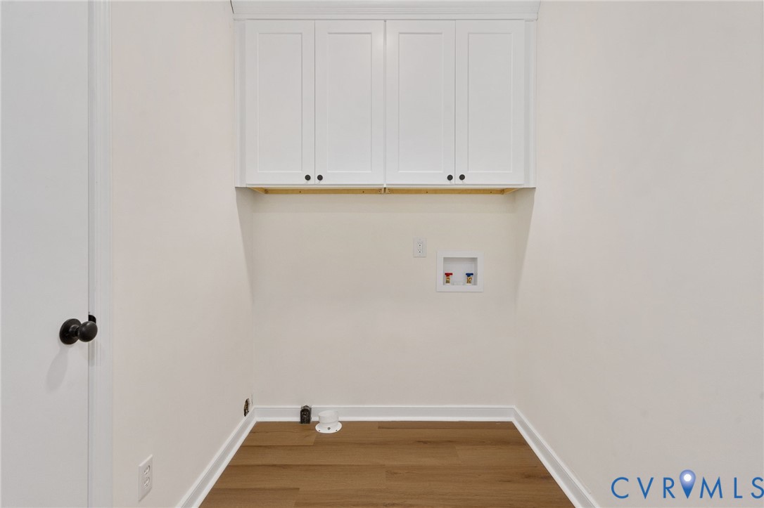 Laundry area with wood-finish flooring, white shaker-style cabinetry, and a utility hookup