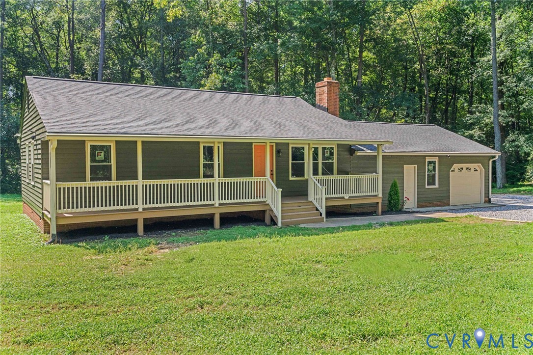 Ranch-style residence featuring a covered front porch, attached garage, and a prominent brick chimney Ranch-style residence featuring a covered front porch, attached garage, and a prominent brick chimney