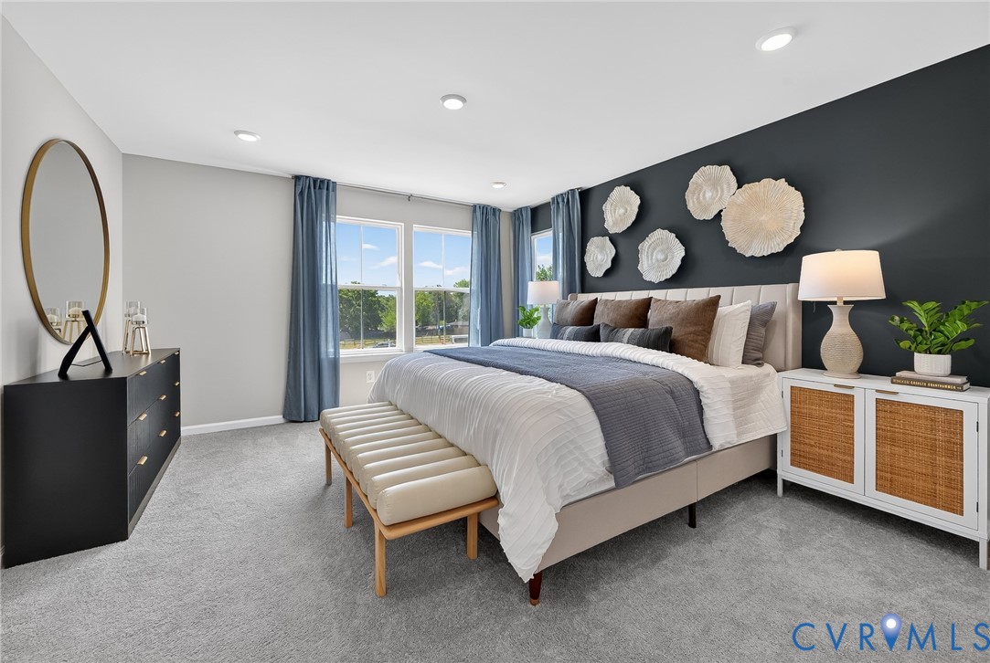 Recessed lighting, light gray carpet flooring, large windows with blue drapery, accent wall, and a headboard