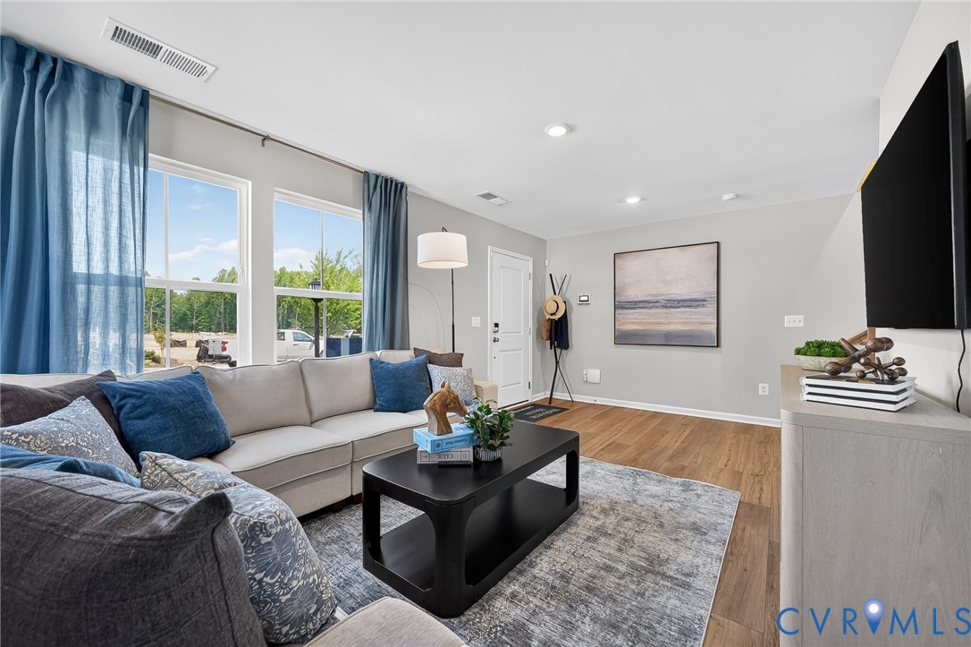 Recessed lighting, wood-finish flooring, white trim, and a large window