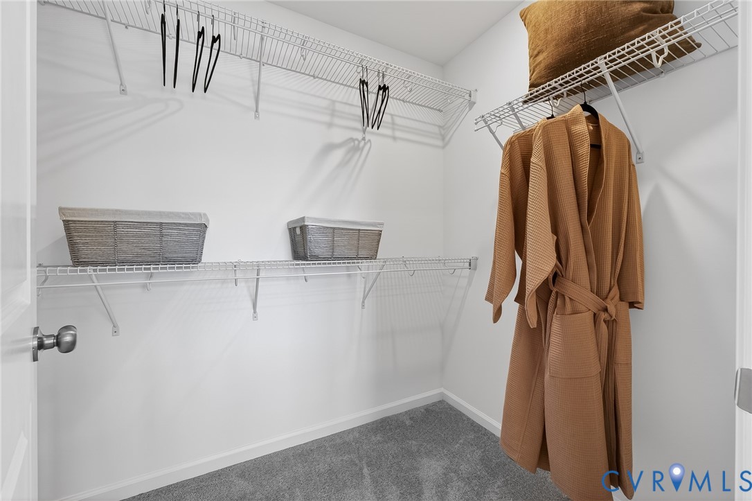 Walk-in closet with carpet flooring, white wire shelving, and hanging rods