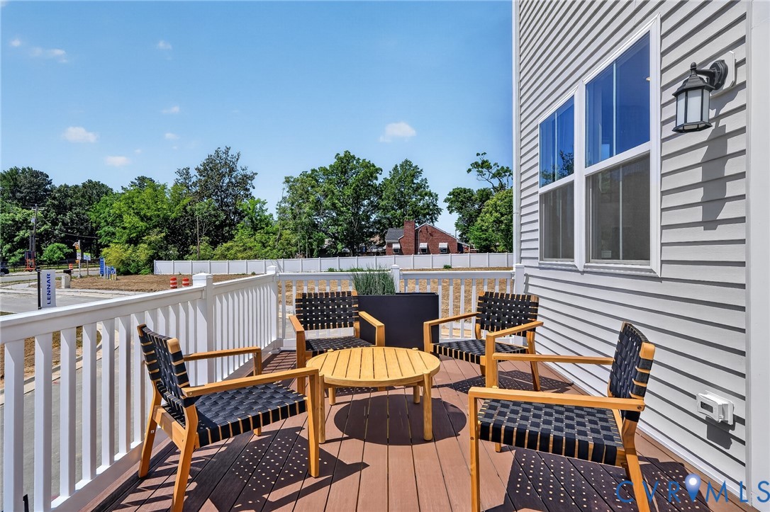 Outdoor deck with wood-finish flooring, white railing, and exterior wall sconce