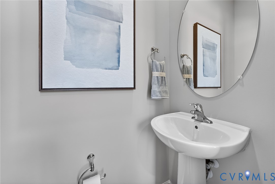 Pedestal sink with a chrome faucet, oval mirror, and chrome towel ring
