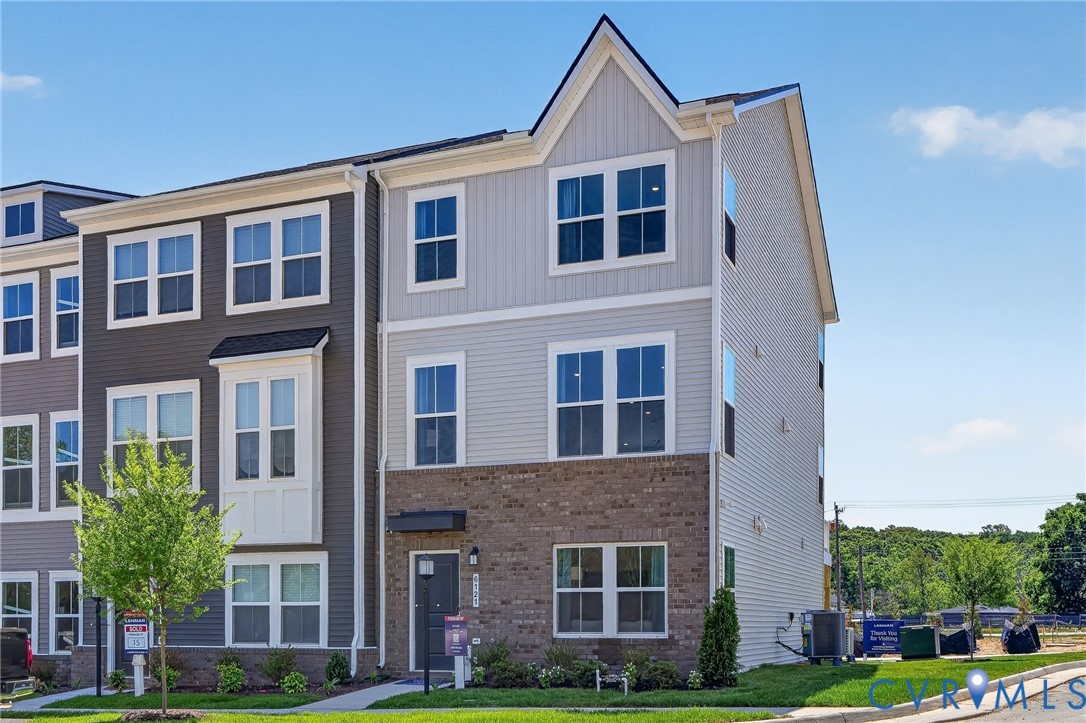Modern townhome with multi-tone siding, brick accents, and a prominent gable roofline