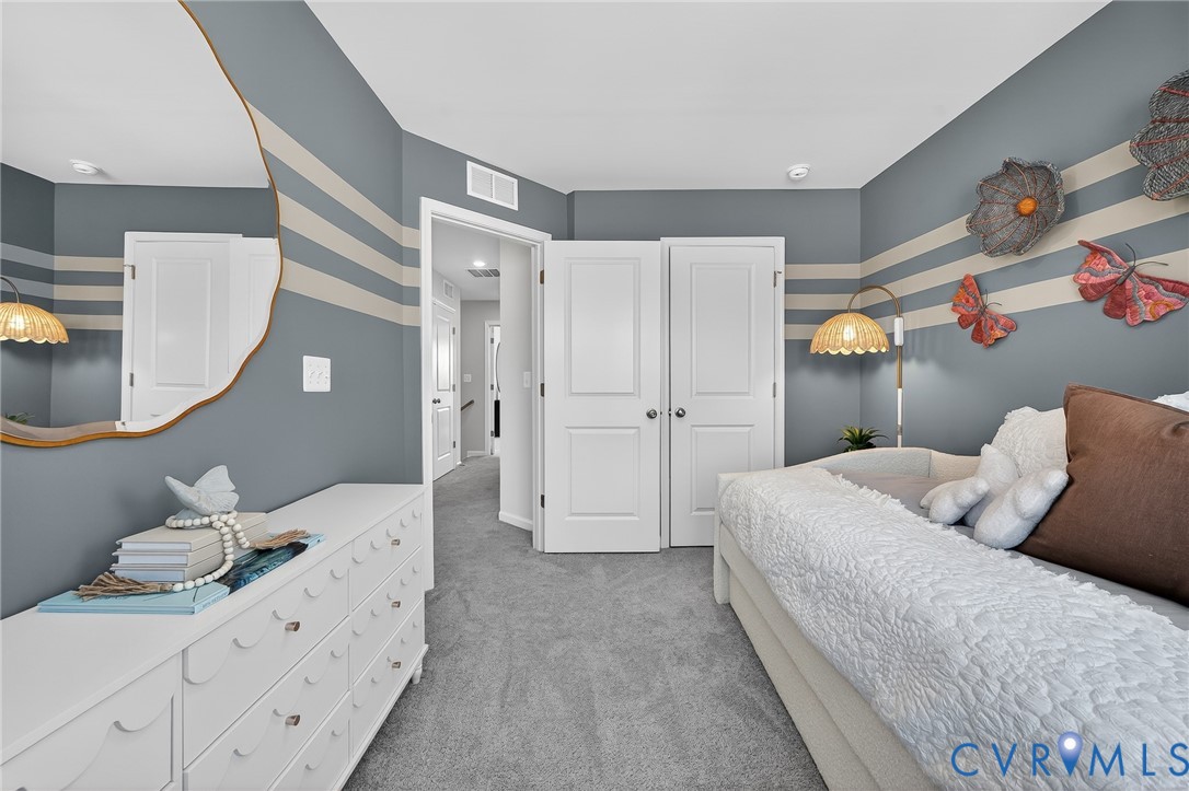 Wall-to-wall carpeting, painted accent wall, white paneled doors, and ceiling-mounted light fixtures
