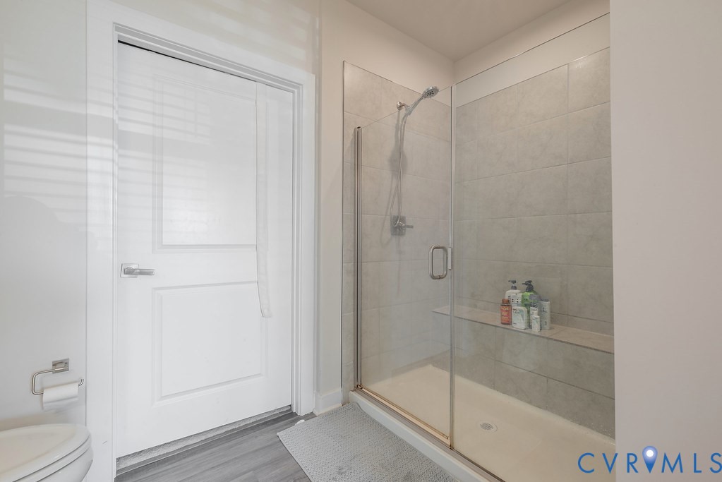 Glass-enclosed shower with tile surround and built-in shelf