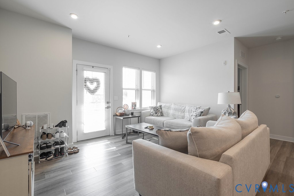 Open-concept living area featuring recessed lighting, wood-finish flooring, and multiple windows for natural light