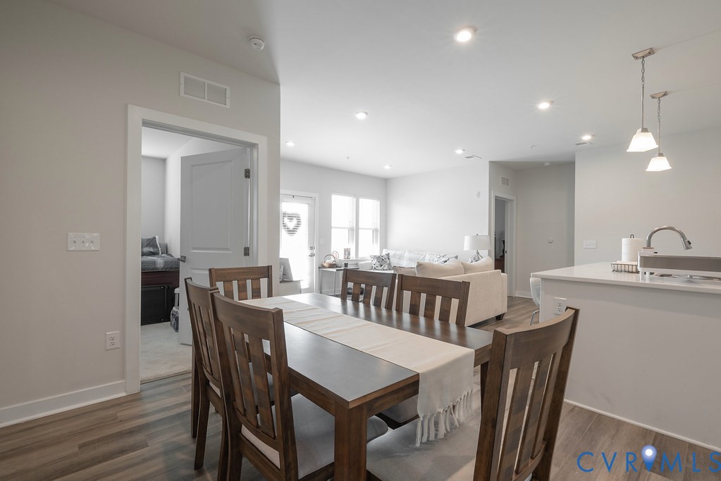 Open-concept living space featuring wood-finish flooring, recessed lighting, and a kitchen island with pendant lighting Open-concept living space featuring wood-finish flooring, recessed lighting, and a kitchen island with pendant lighting