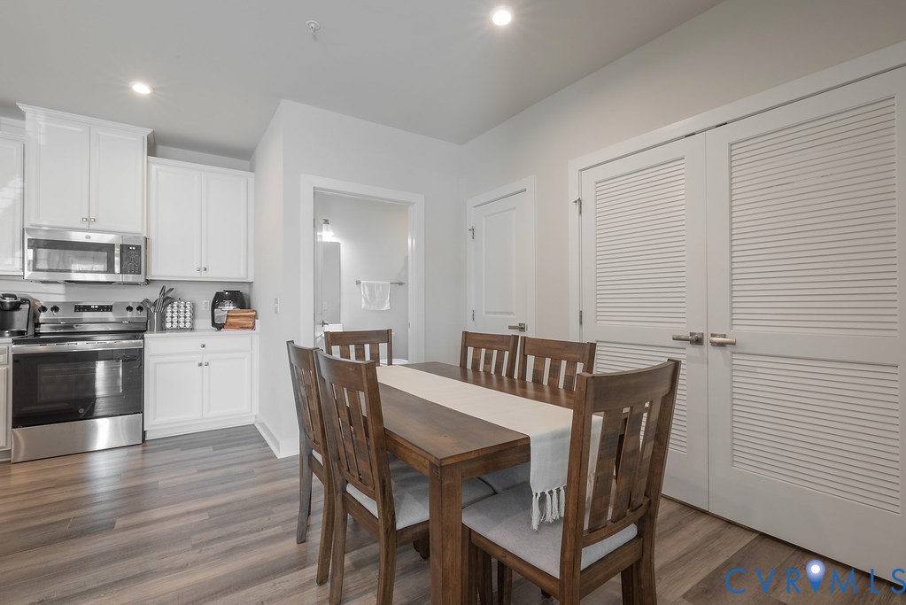 Kitchen featuring white cabinetry, stainless steel appliances, and wood-finish flooring Kitchen featuring white cabinetry, stainless steel appliances, and wood-finish flooring