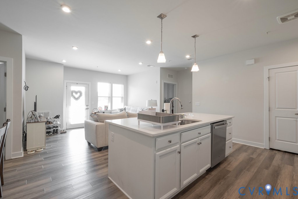 Open-concept living space featuring wood-finish flooring, recessed lighting, and a kitchen island with pendant lighting Open-concept living space featuring wood-finish flooring, recessed lighting, and a kitchen island with pendant lighting