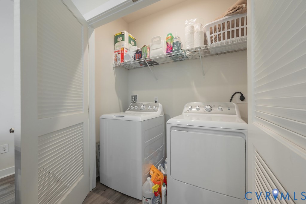 Laundry closet featuring a built-in wire shelf, louvered bi-fold doors, and wood-finish flooring