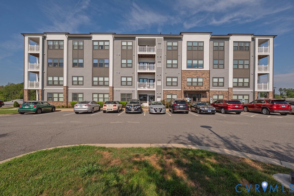 Multi-story building featuring a blend of gray siding, stone accents, and white trim