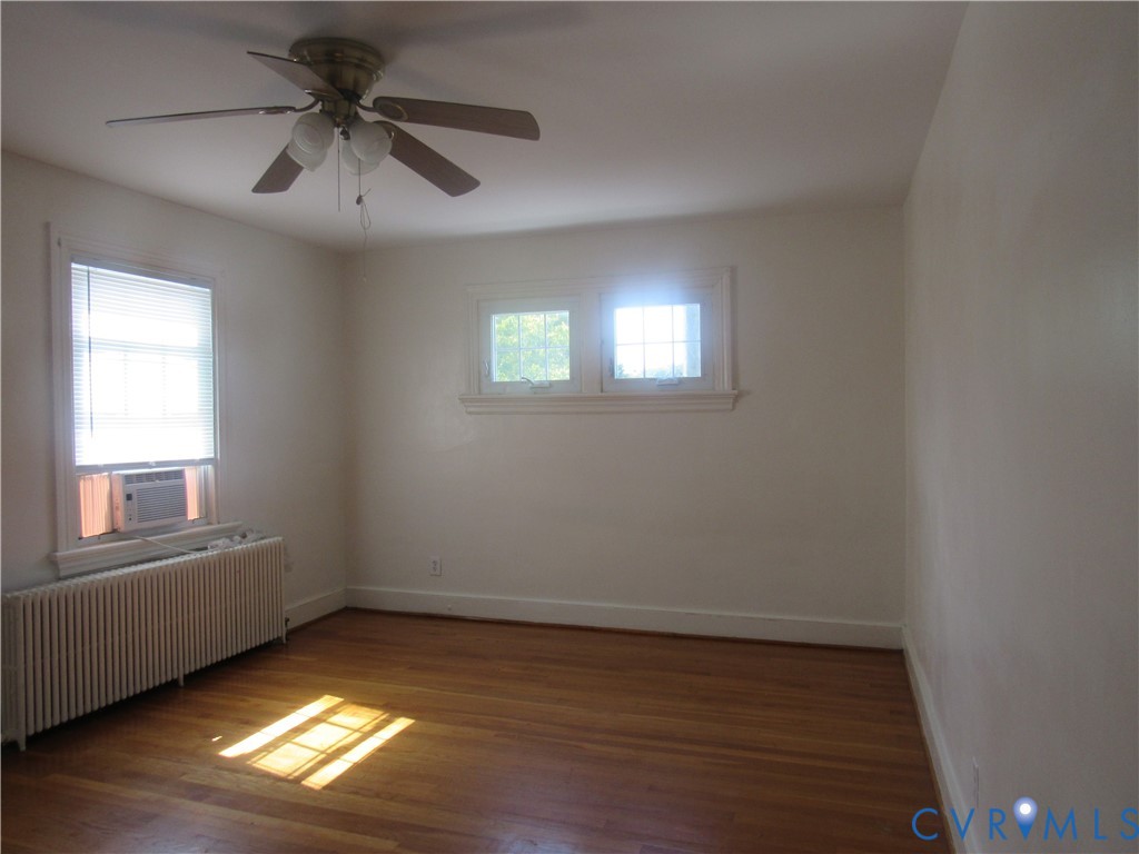 Wood-finish flooring with white trim and a ceiling fan