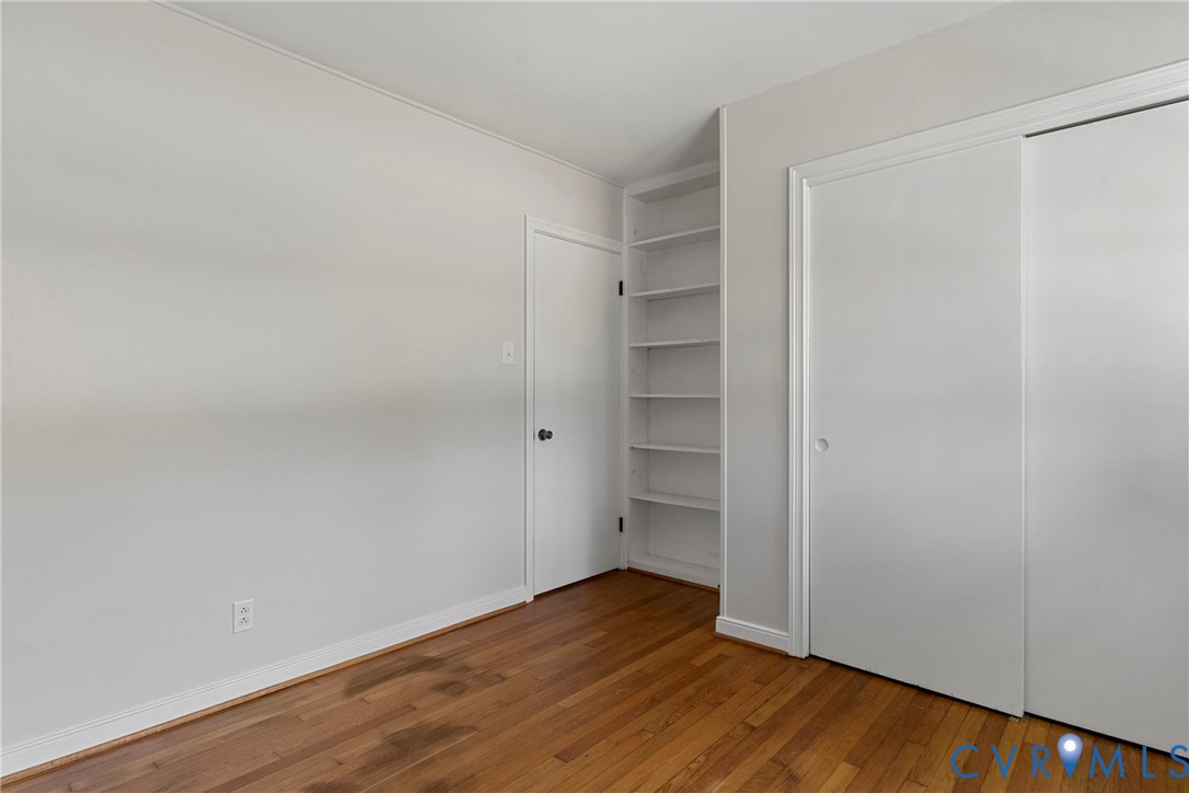 Hardwood flooring, built-in shelving, two white doors, and light-toned walls
