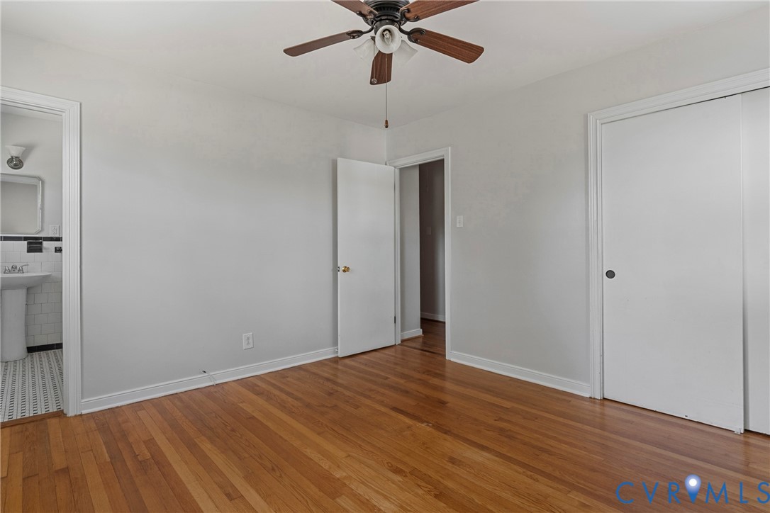 Hardwood flooring, ceiling fan with integrated lighting, and a white interior door with a dark knob