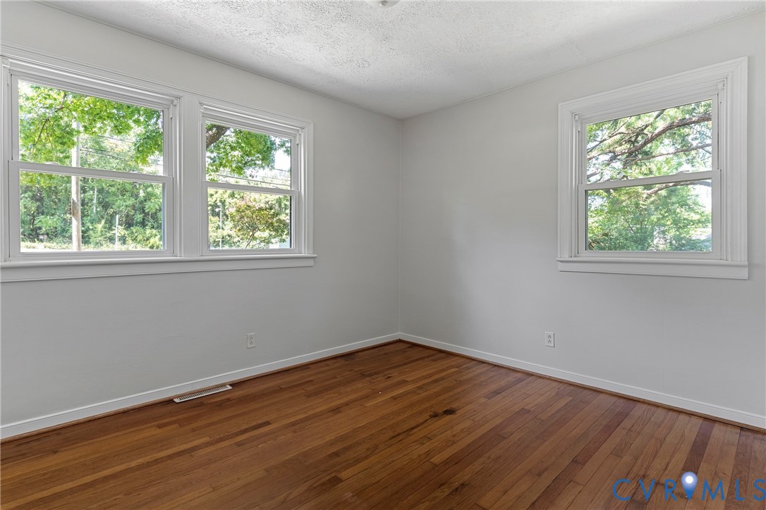 Hardwood flooring, painted white walls, two double-hung windows, and a single-hung window
