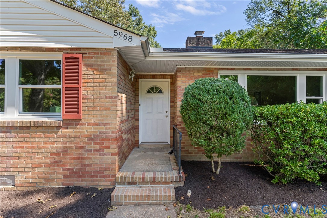Brick exterior with white trim, a white front door, and red window shutters
