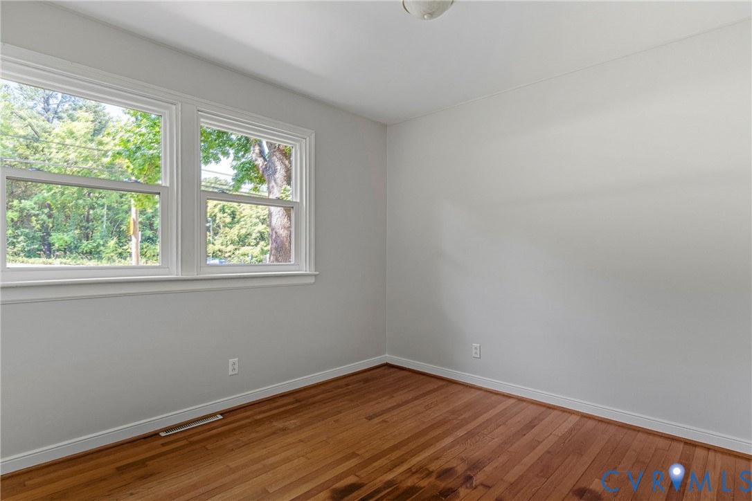 Hardwood flooring, dual windows with white trim, light gray wall paint, and a ceiling-mounted light fixture