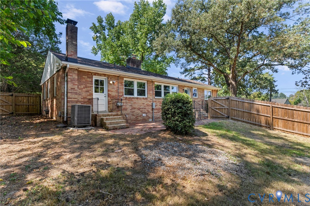 Brick exterior with multiple windows and a wooden privacy fence