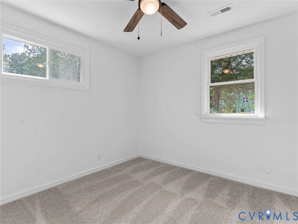 Room featuring neutral carpeting, white walls, and a ceiling fan with light fixture