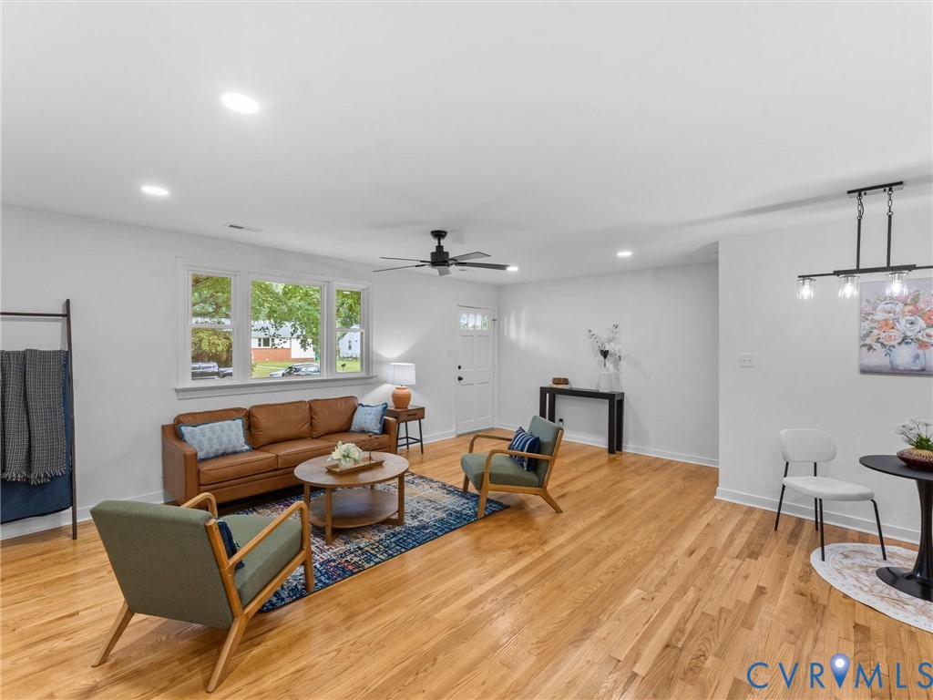 Hardwood flooring, recessed lighting, ceiling fan, white paneled entry door, and large multi-pane window