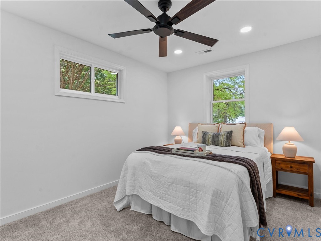 Recessed lighting, ceiling fan with wood-finish blades, white walls, and light gray carpet