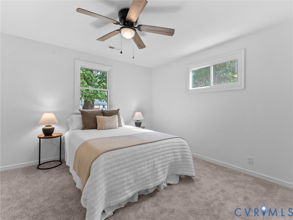 Recessed lighting, ceiling fan with light fixture, two windows, and light-colored carpeting