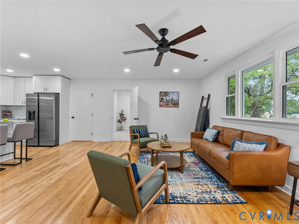 Open-concept living space featuring wood-finish flooring, a contemporary ceiling fan, and recessed lighting Open-concept living space featuring wood-finish flooring, a contemporary ceiling fan, and recessed lighting