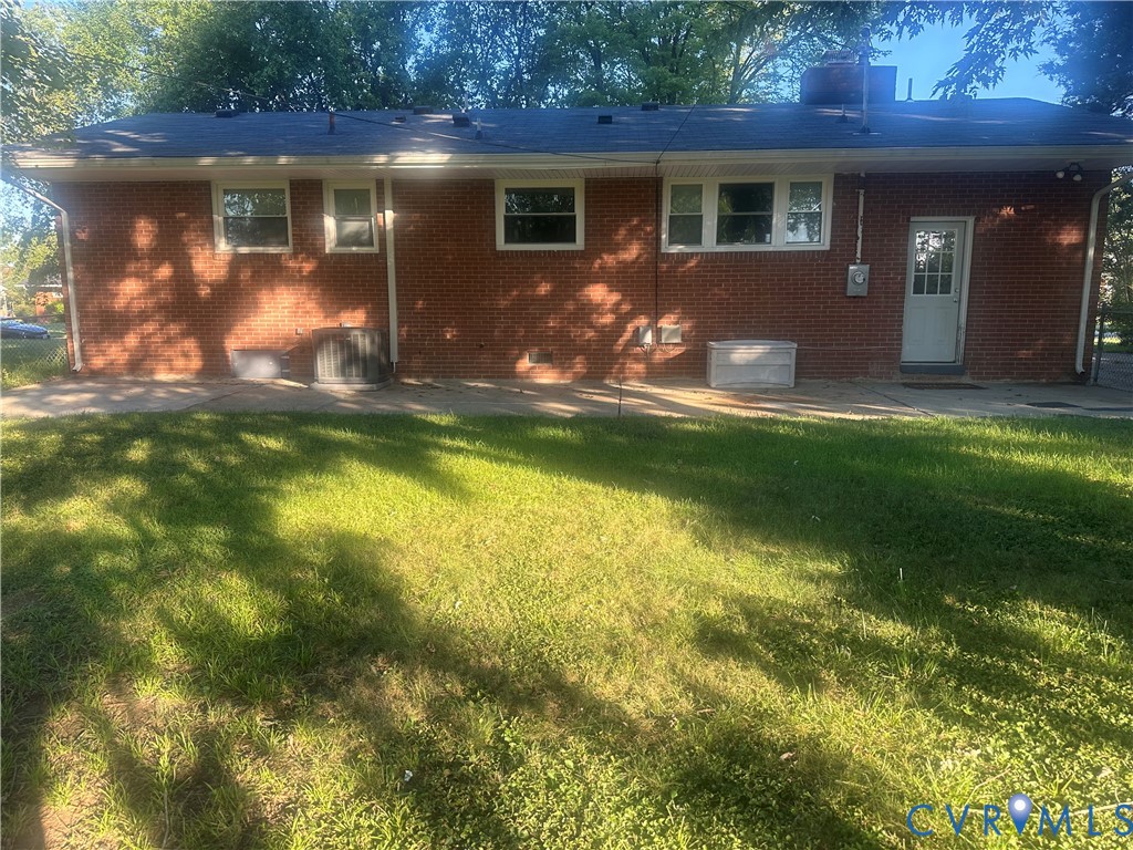 Brick exterior with multiple windows, a white rear entry door, and a level lawn area Brick exterior with multiple windows, a white rear entry door, and a level lawn area