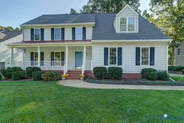 Two-story siding exterior with dark shutters, covered front porch, and dormer window