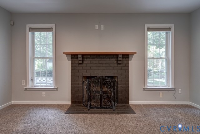 Brick fireplace with a wood-finish mantel and hearth, flanked by two single-hung windows