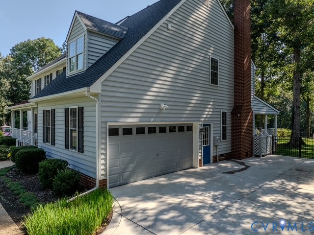 Traditional exterior with light blue siding, a two-car garage, a brick chimney, and a concrete driveway