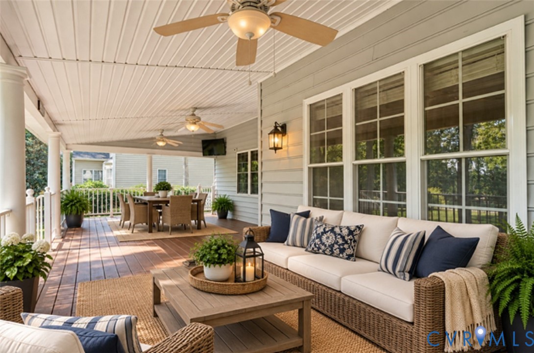Expansive covered patio featuring a wood-finish floor, multiple ceiling fans, and white paneled ceiling