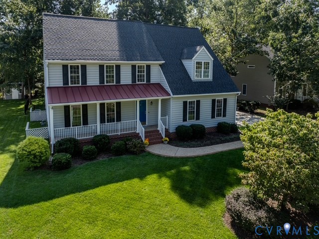 Two-story Colonial home featuring light-colored siding, a dark shingled roof, and a red metal-roofed front porch