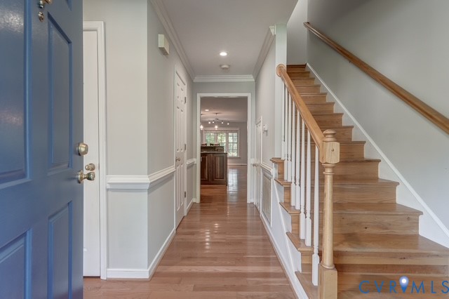 Hardwood flooring throughout the entryway, leading to a wooden staircase
