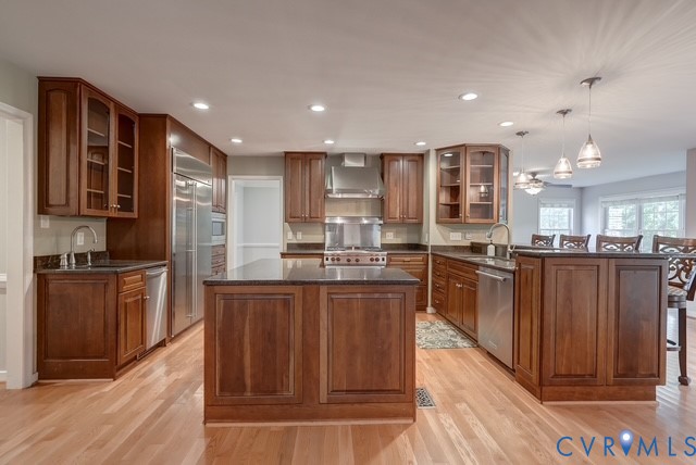 Kitchen featuring hardwood flooring, dark wood cabinetry, stainless steel appliances, recessed lighting, and a central island with countertop