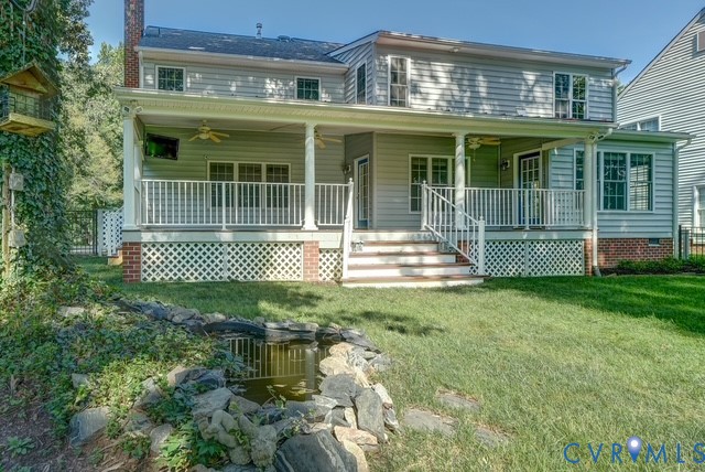 Rear exterior featuring a covered porch with ceiling fans, white railing, and lattice skirting