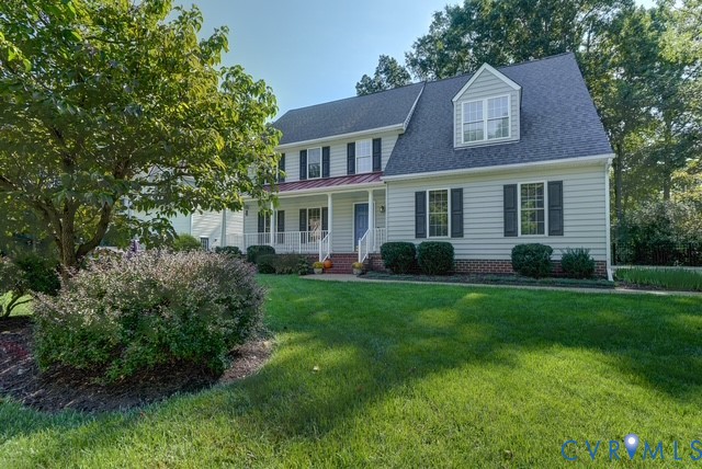 Two-story residence with dormer window, covered front porch, and mature trees
