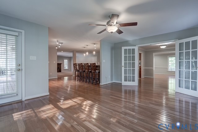 Sitting Room with French Doors leading to the Dining Room. Wood-finish flooring, ceiling fan with light fixture, French doors, recessed lighting, and a kitchen island with pendant lighting